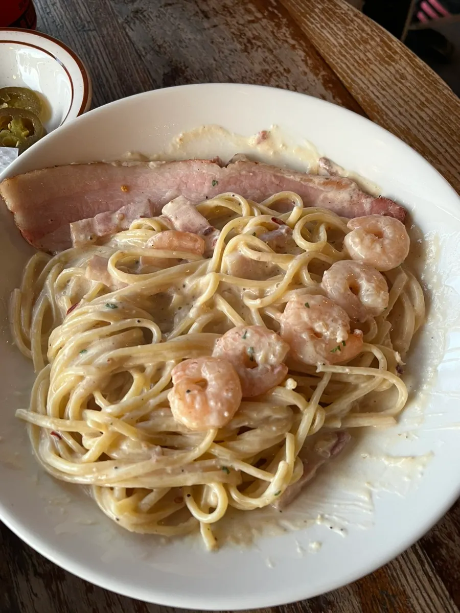 Alfredo cream pasta topped with whole bacon and shrimp