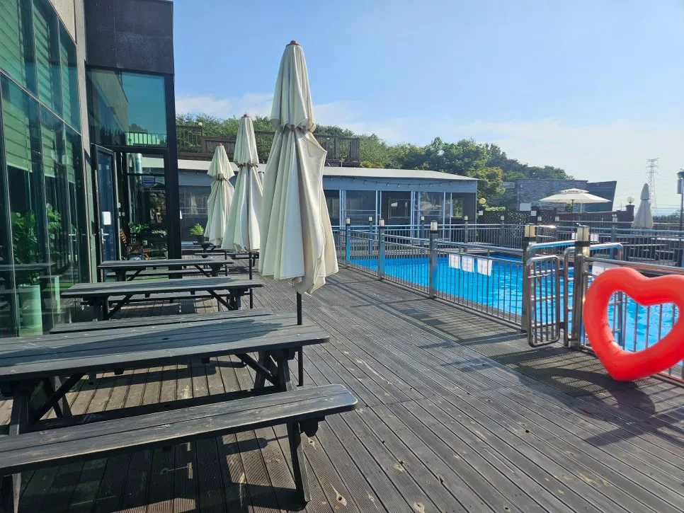 Pool deck lined with parasols and picnic tables