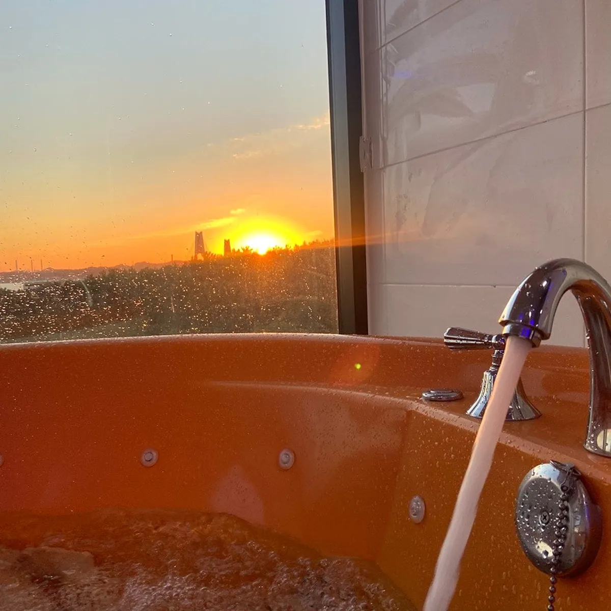 Ocean-view spa tub with the sunset visible
