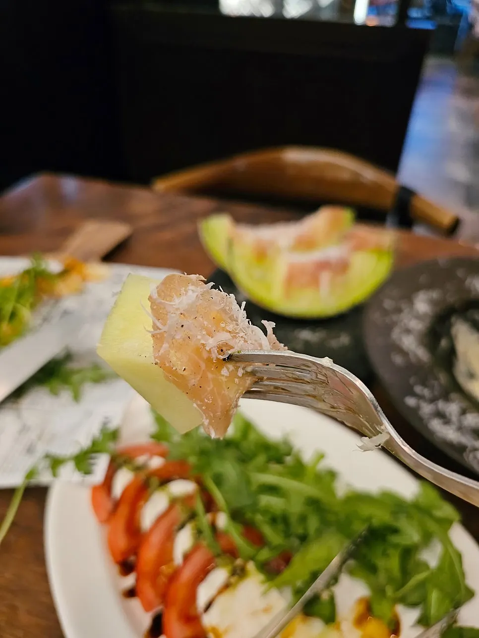 A plate of melon prosciutto topped with cheese powder