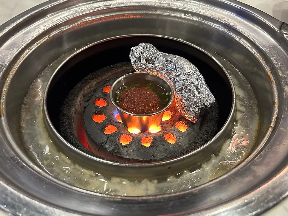 Black pork neck being pre-grilled over charcoal