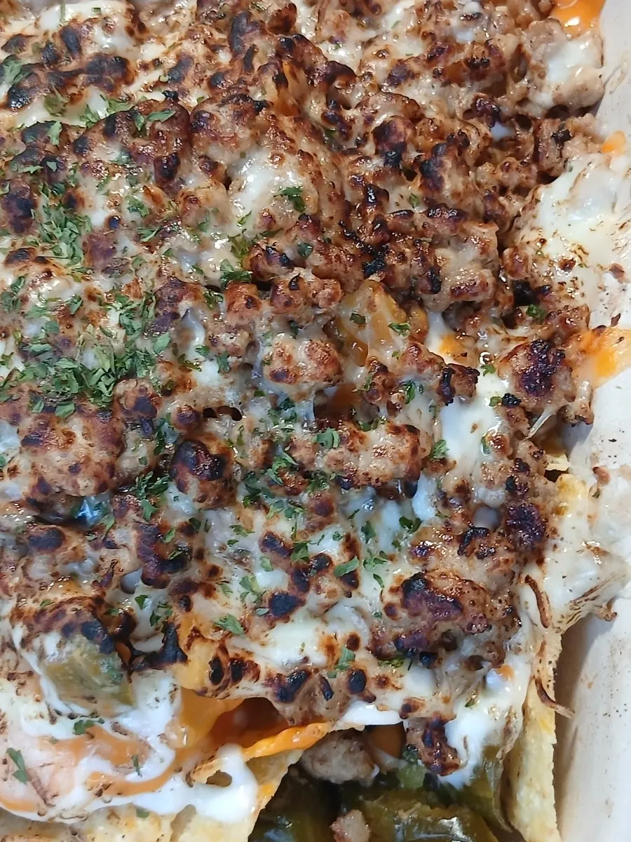 A plate of nachos with toppings still left near the end