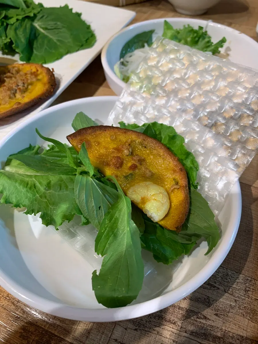 A wrap of banh khot with herbs