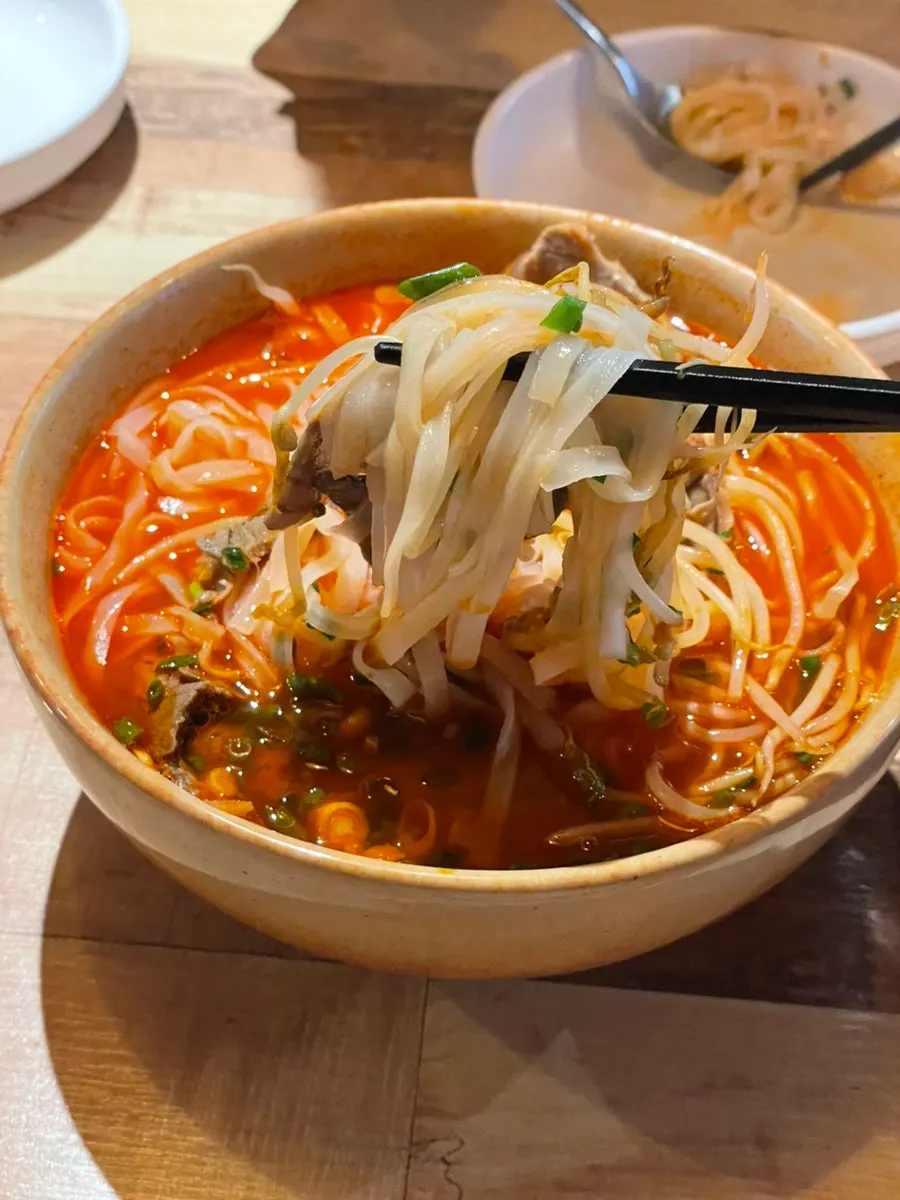 A chopstick-lifted bite of jjamppong pho