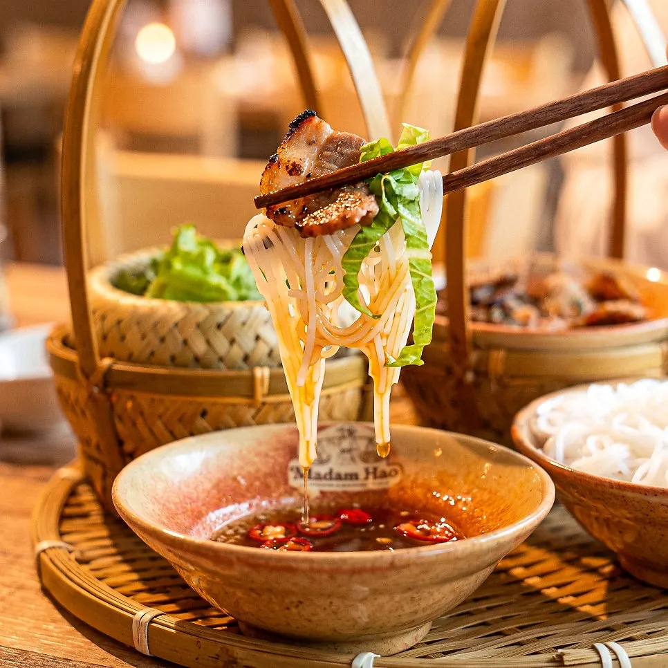 Bowl of nuoc mam sauce with bun cha components