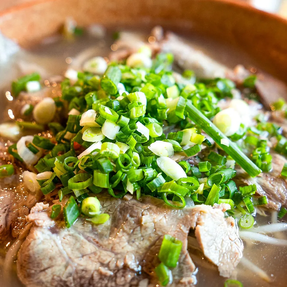 Lifting pho noodles and brisket with chopsticks