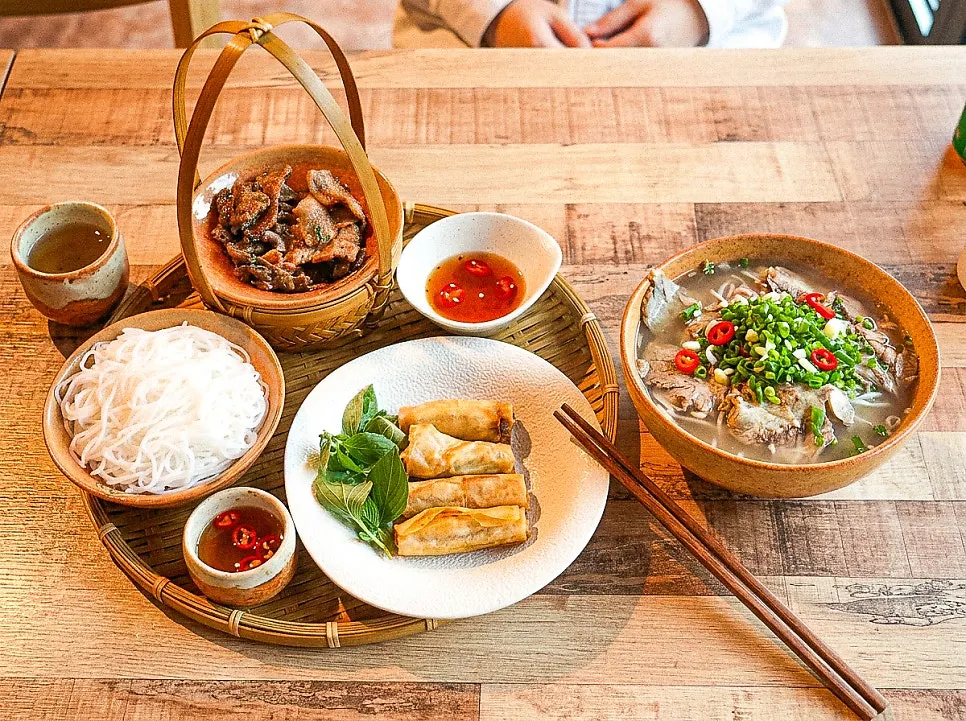 Table with beef brisket pho, bun cha, and cha gio together