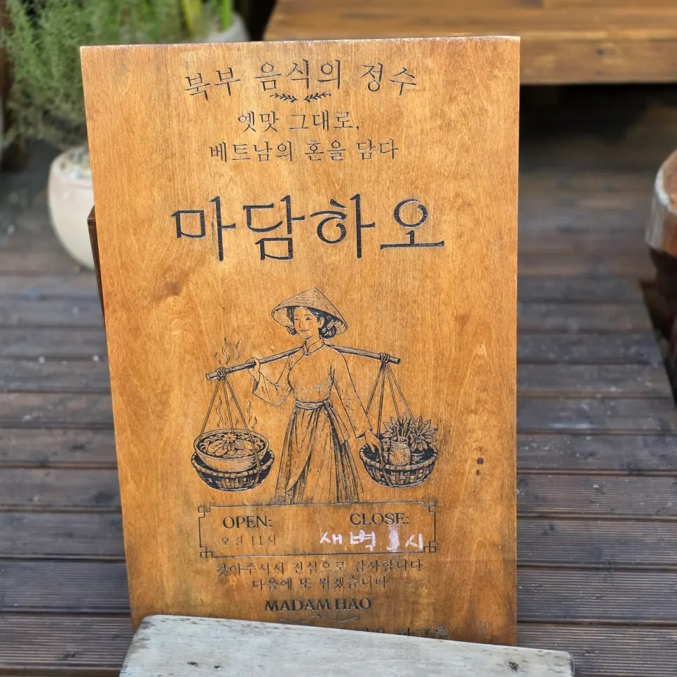 Wooden A-frame sign at Madam Hao's entrance showing business hours