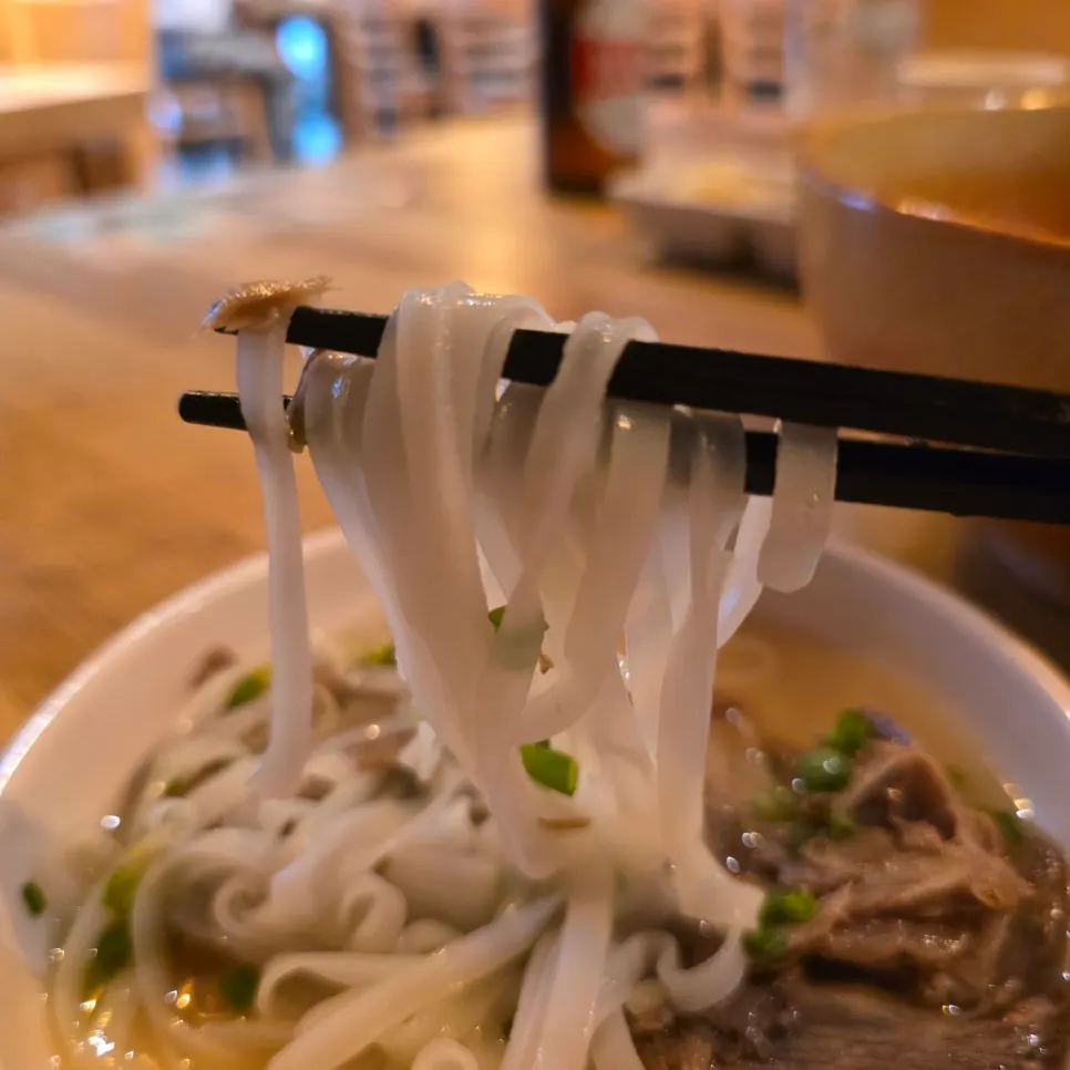 Pho noodles lifted with chopsticks