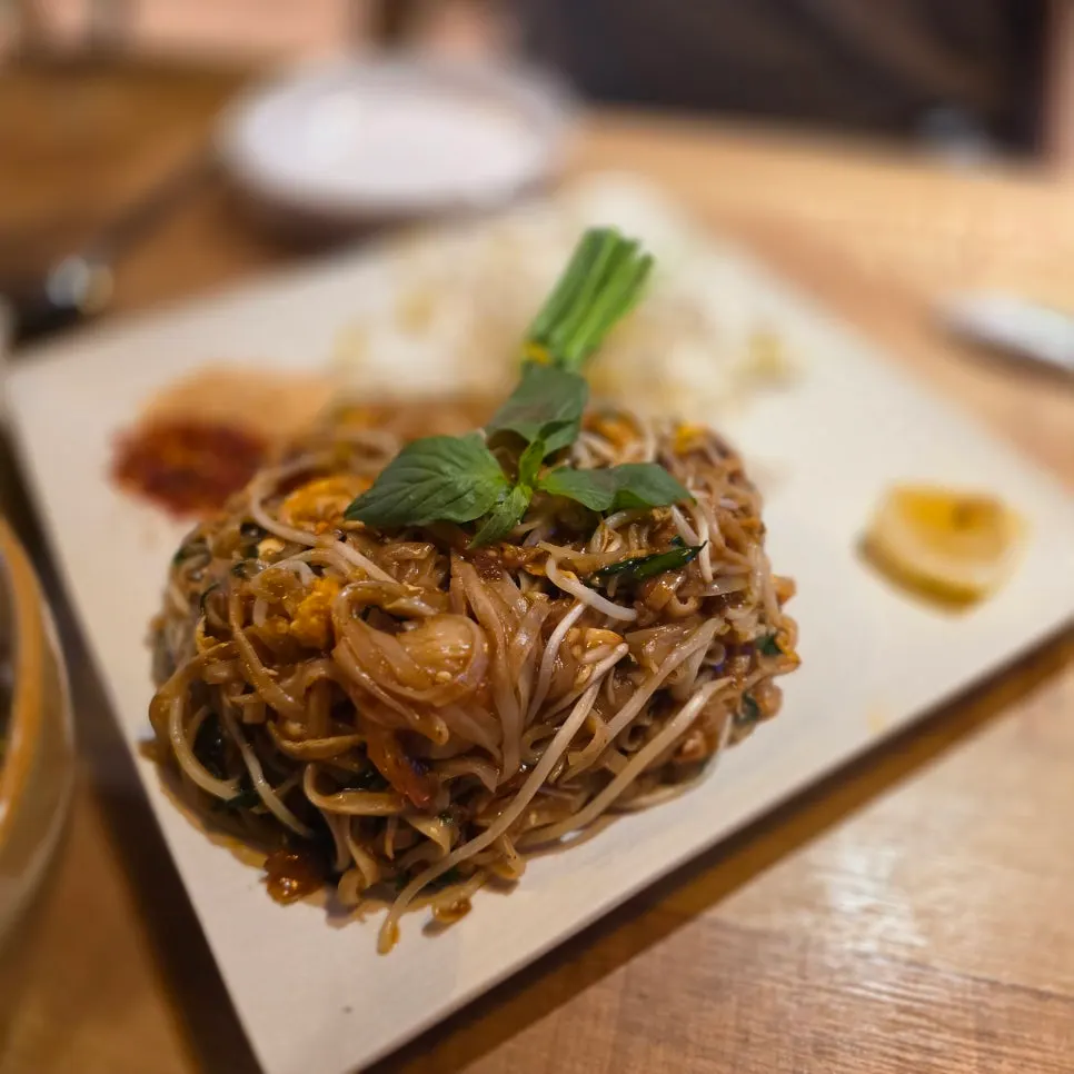 Pad thai topped with herb leaves and crushed peanuts