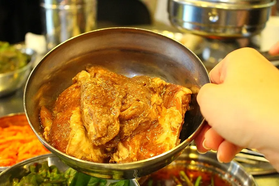 A piece of marinated galbisal with fresh kimchi salad