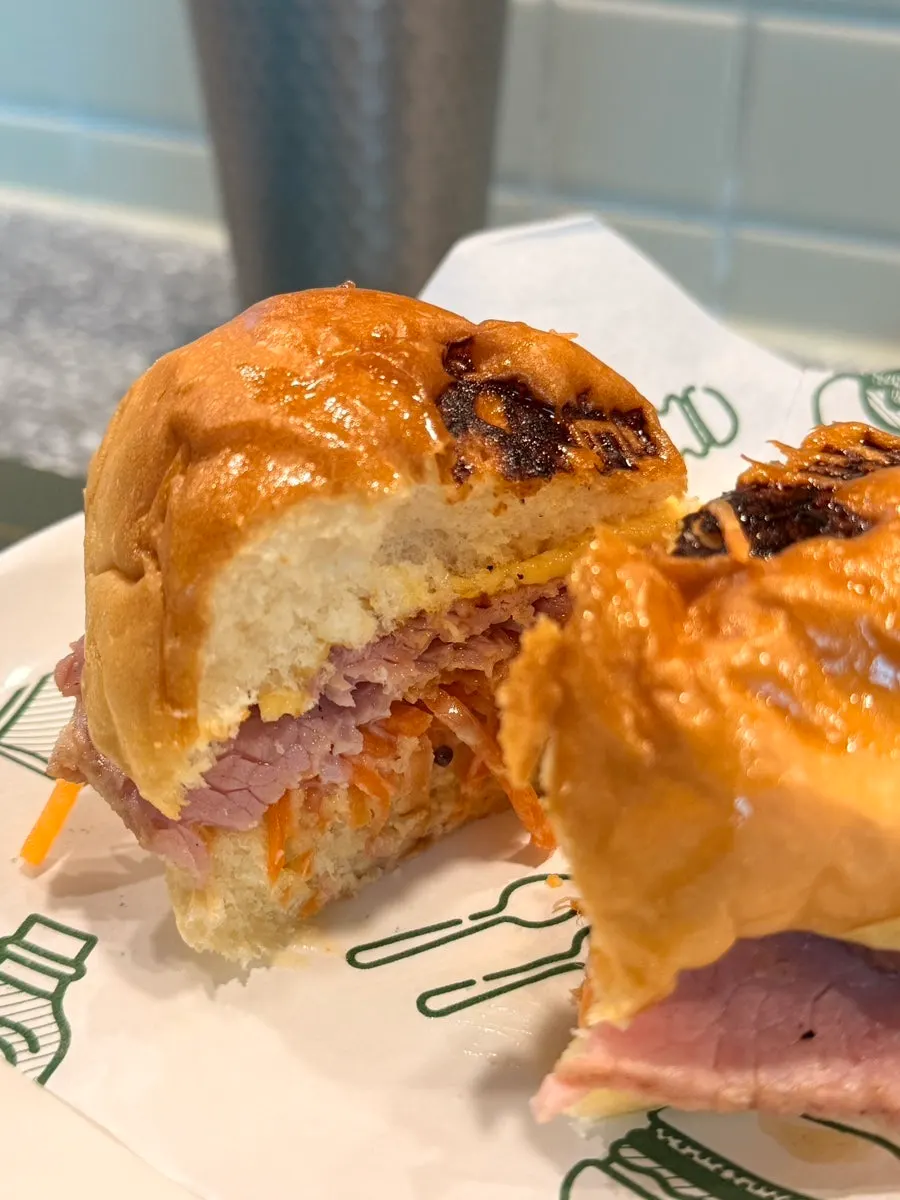 Cross-section of the signature burger packed with carrot slaw and jambon
