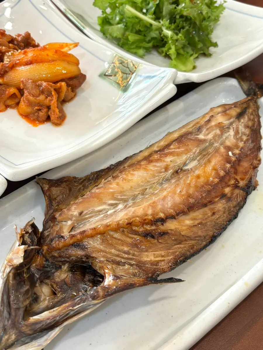 A thick grilled mackerel filling the plate
