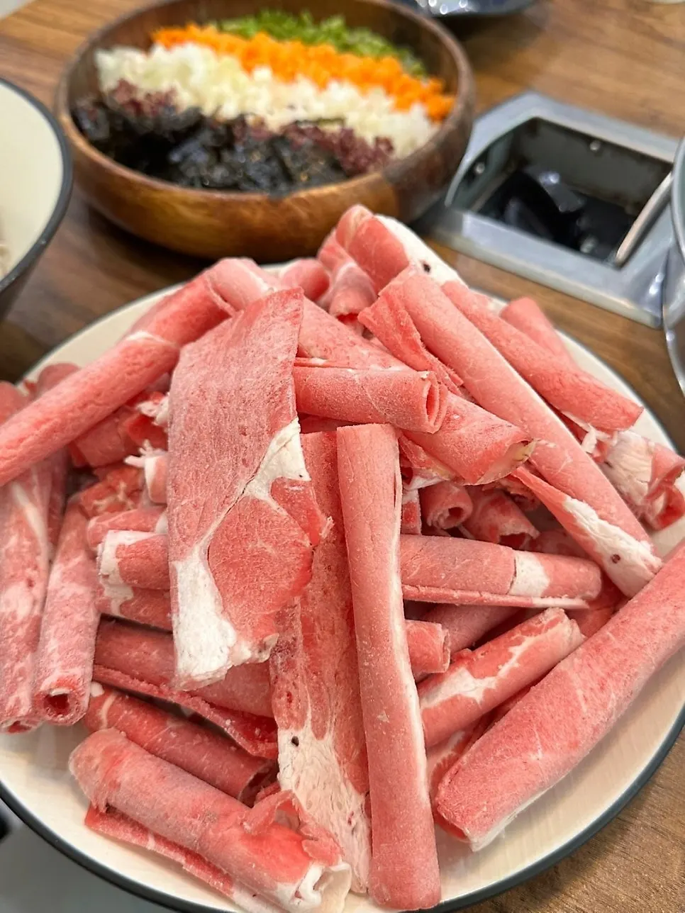 Shabu pot topped with bean sprouts, mushrooms, and minari