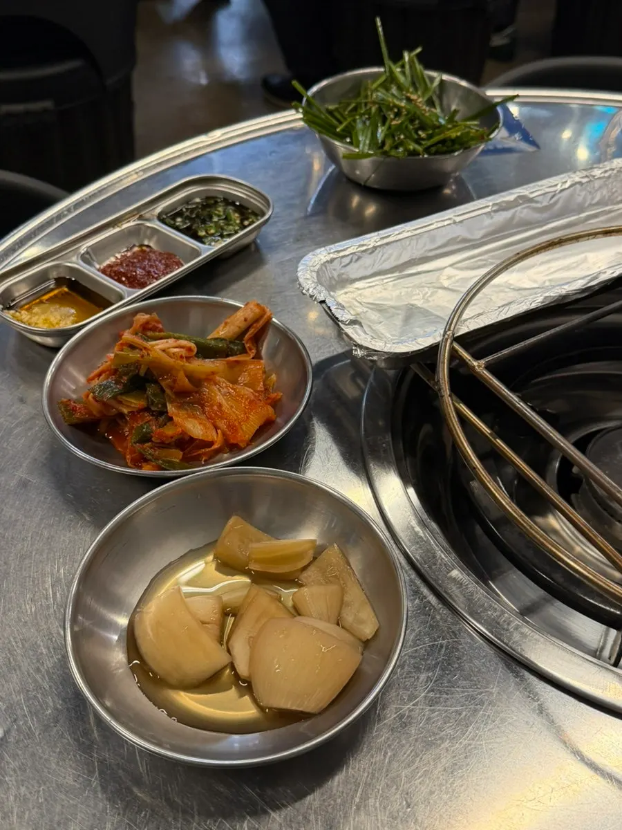 Table of basic side dishes including green onion kimchi and pickled onions
