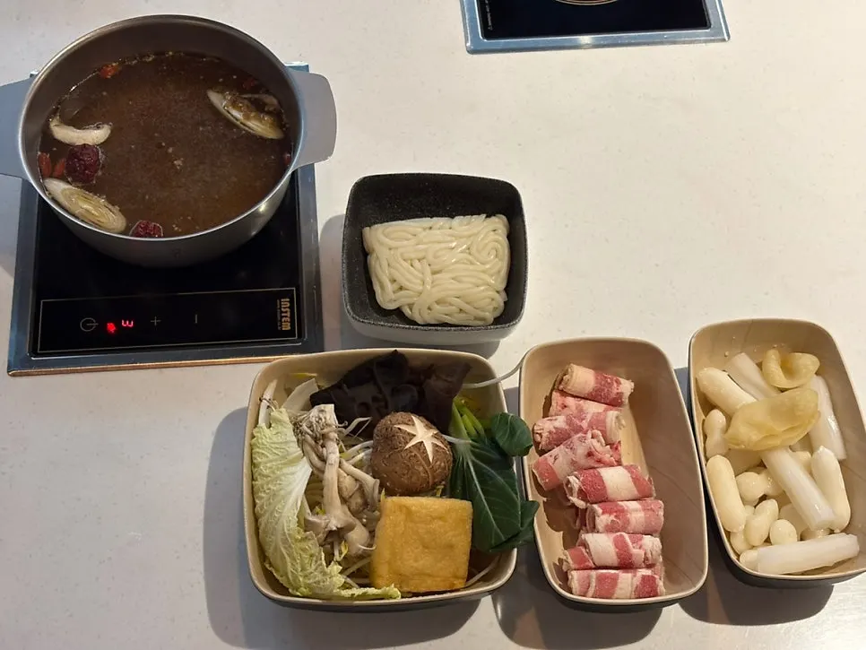 Hot pot on the table with plates of ingredients