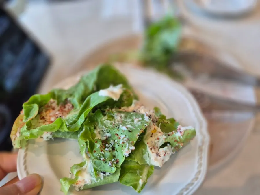 Salad topped with Caesar dressing and maple bacon chips