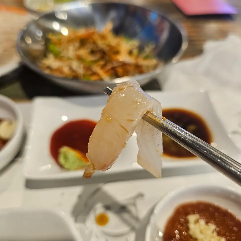 와사비 올려 간장에 찍은 광어회 한 점