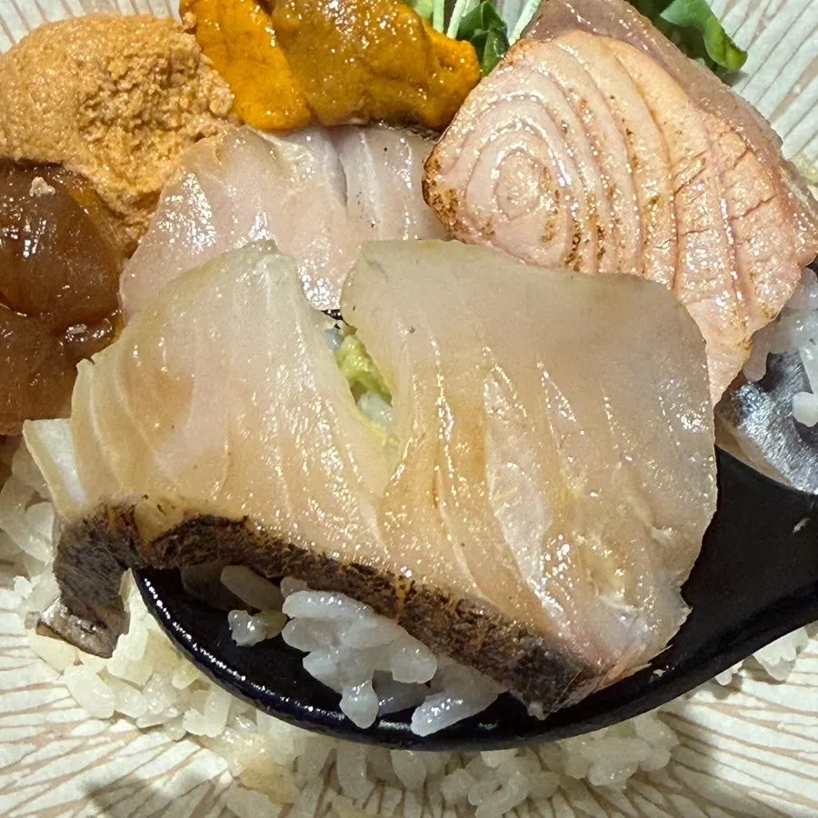 A bite of kaisendon with various salmon preparations
