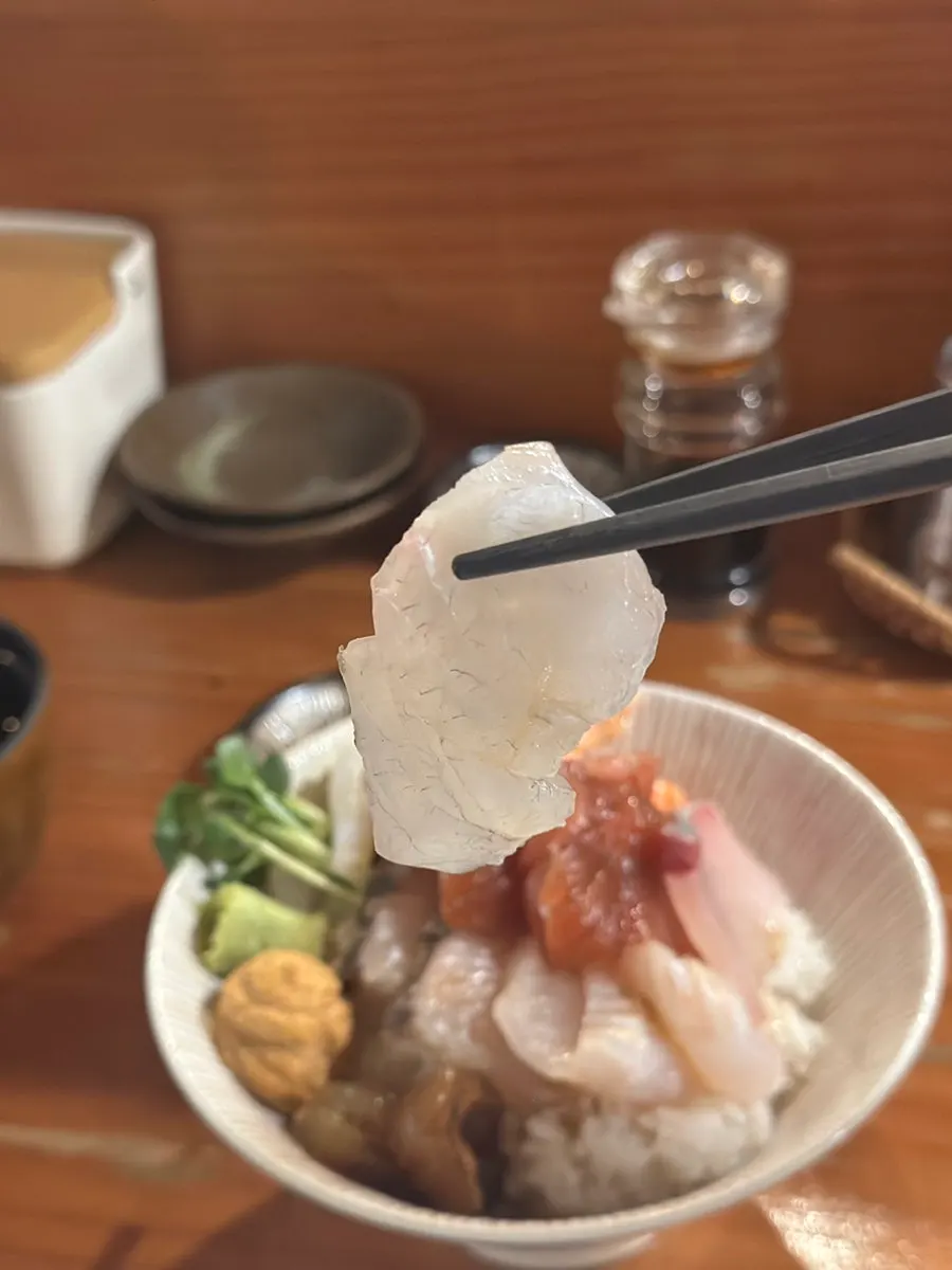 A bite-sized sushi made with rice and sashimi on a spoon