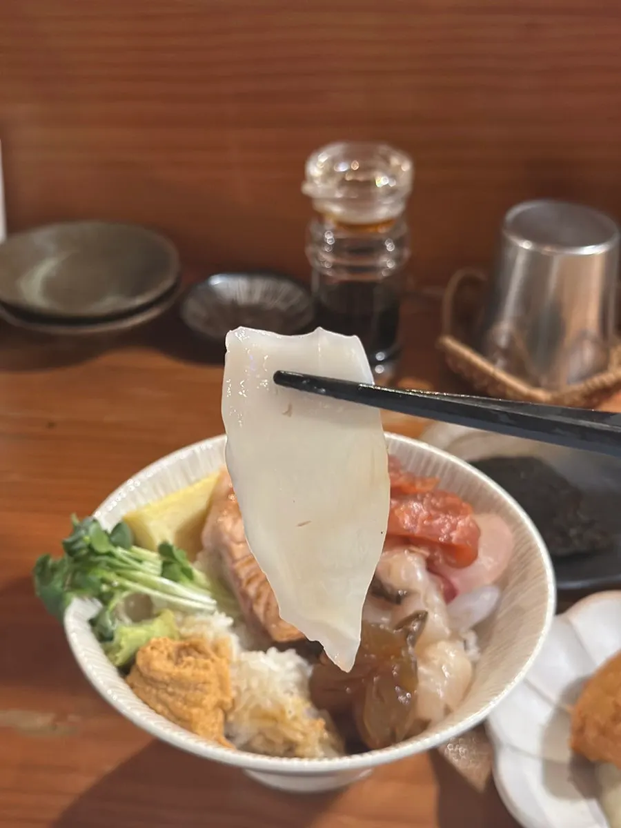 Picking up a piece of sashimi from the kaisendon