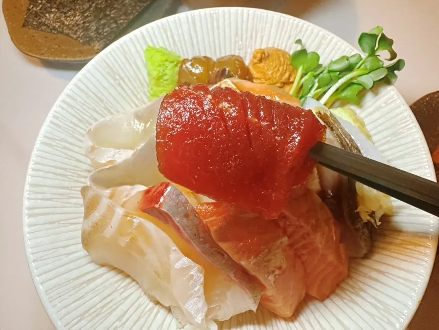 A piece of mackerel sashimi topped with minced seasoning