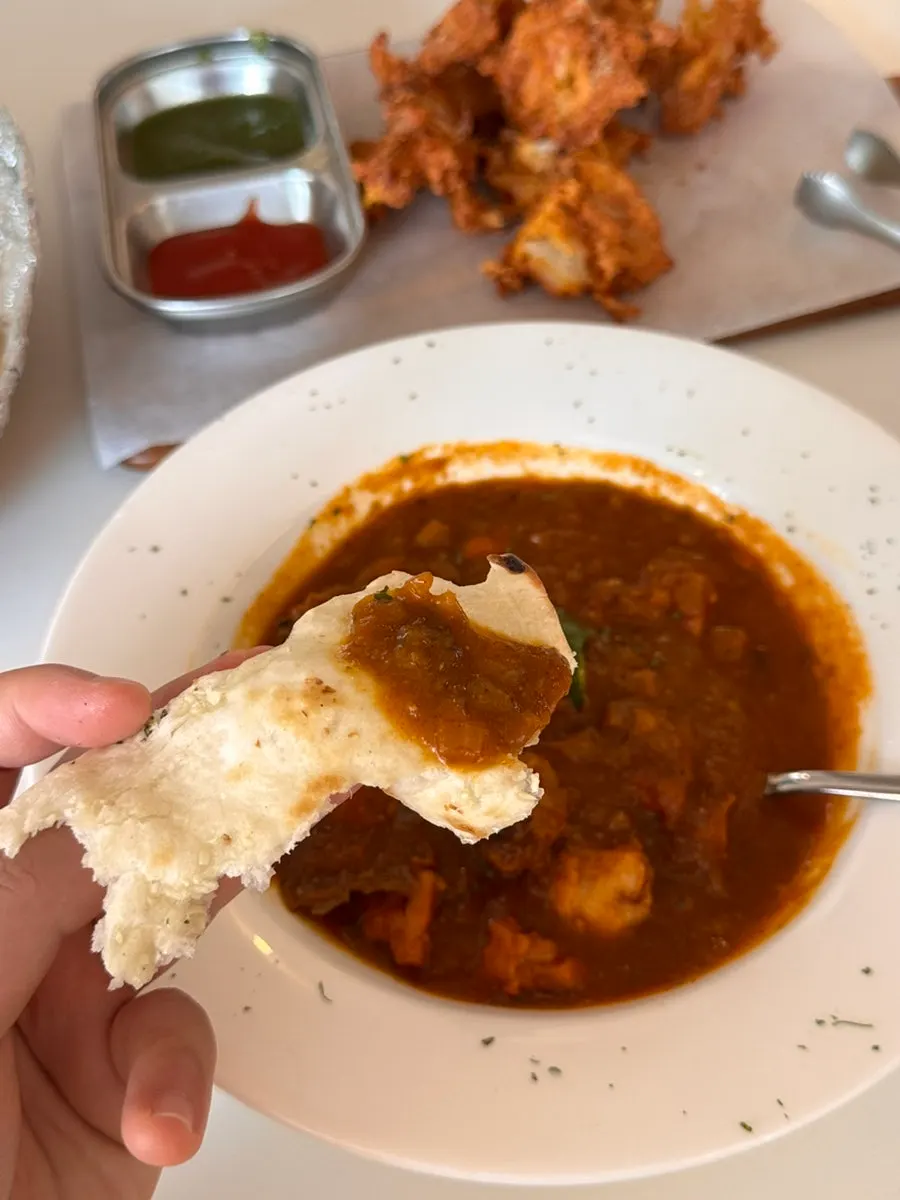 Chicken makhani curry scooped onto naan