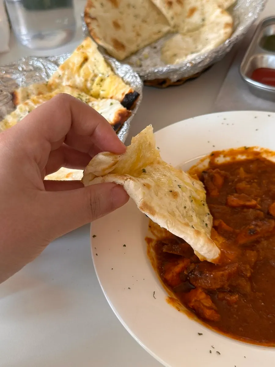 A half-eaten plate of curry and naan