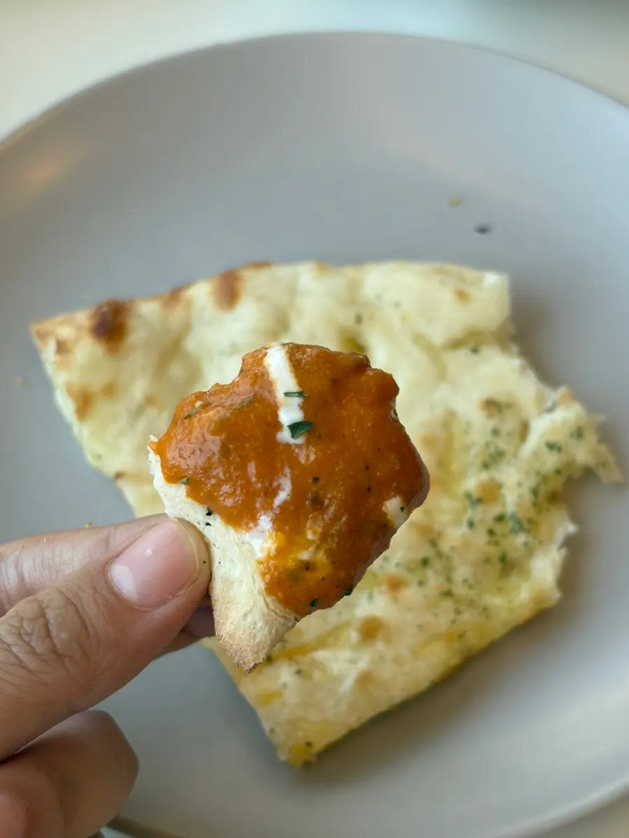 Dipping cheese naan into the curry