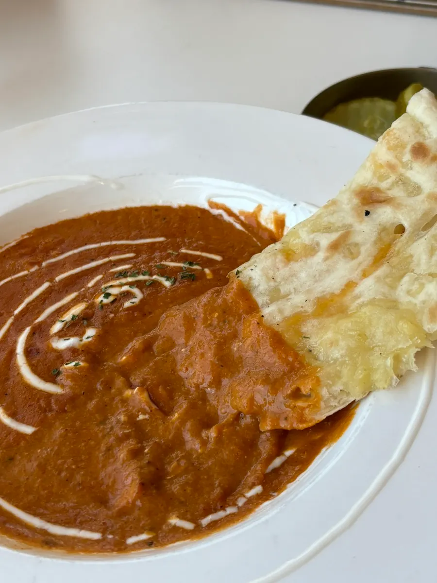 Plate with plenty of curry and naan left over