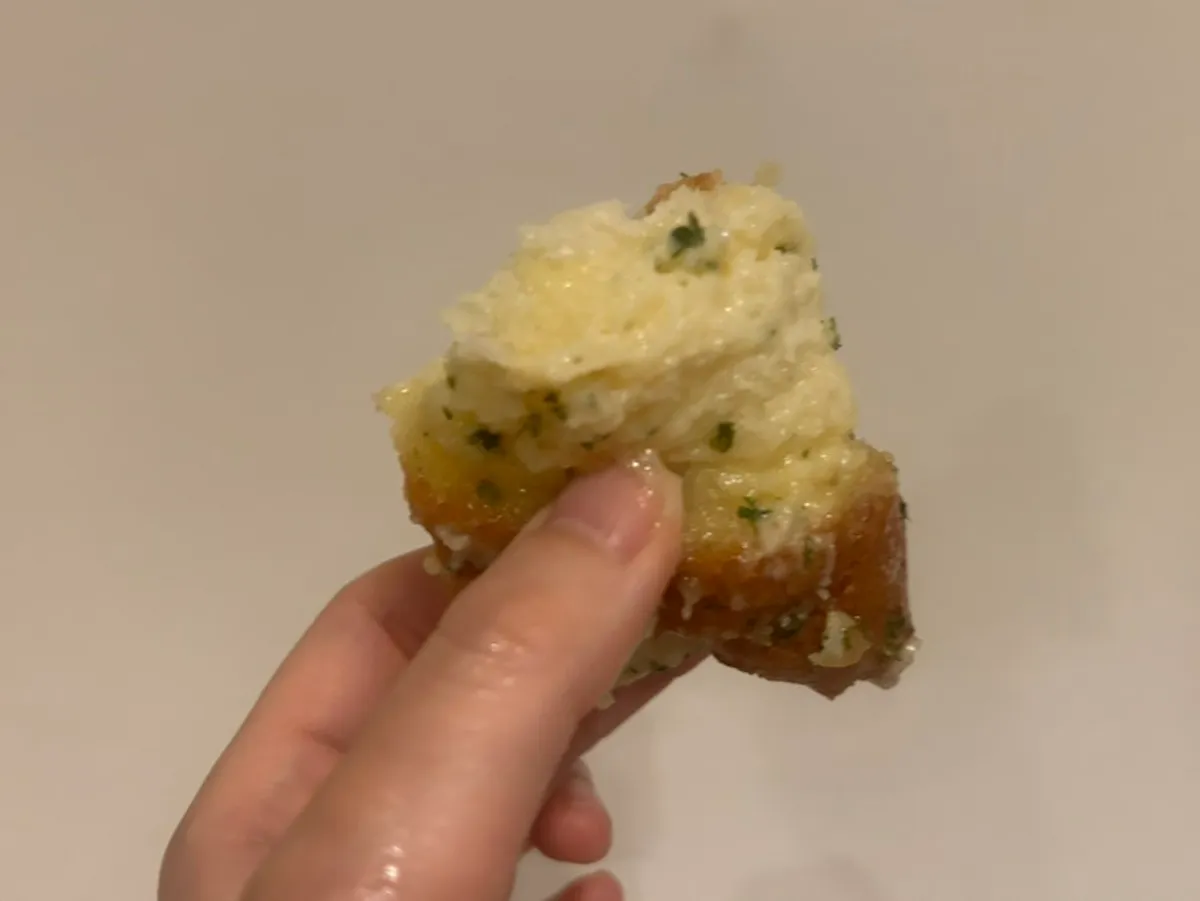 Garlic sauce dripping down a finger from the baguette