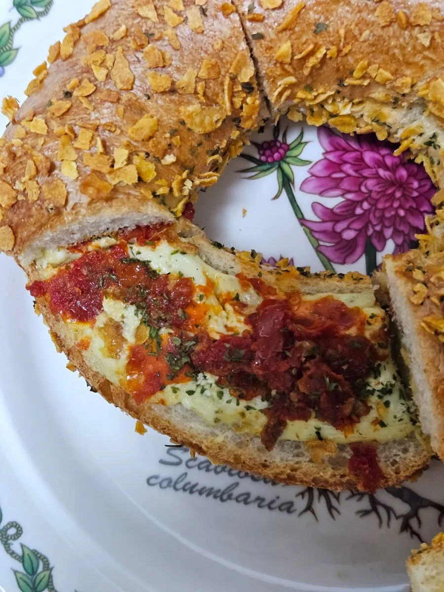 Cross-section of basil tomato bagel showing cream cheese and sun-dried tomato