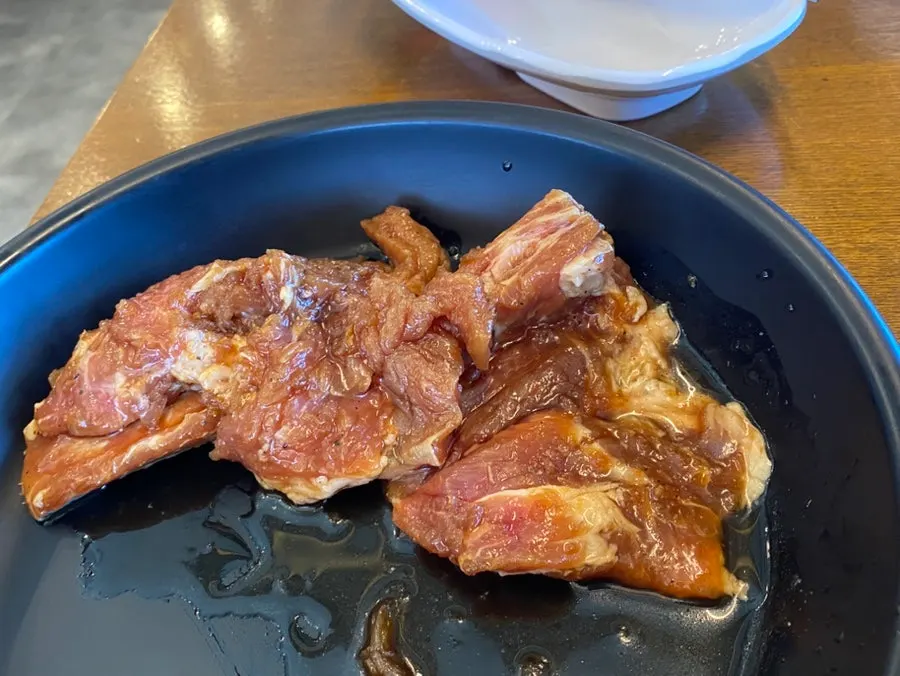 Raw beef short ribs grilling over charcoal