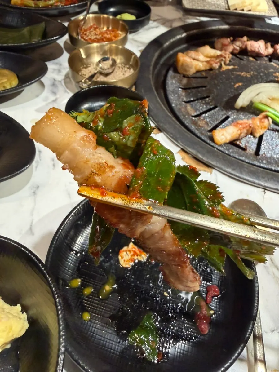 A piece of samgyeopsal topped with gat kimchi