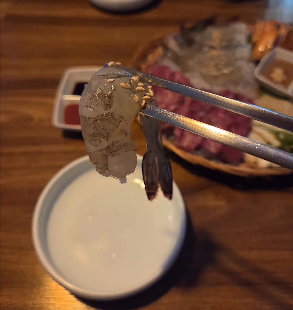 A plate of raw shrimp and beef sashimi