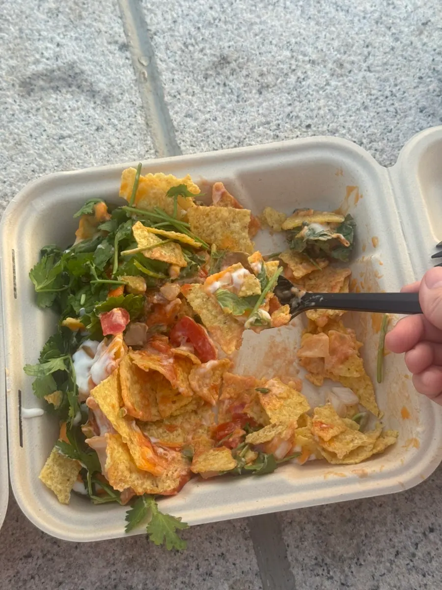 A bite of nacho with dipping cheese and tomato