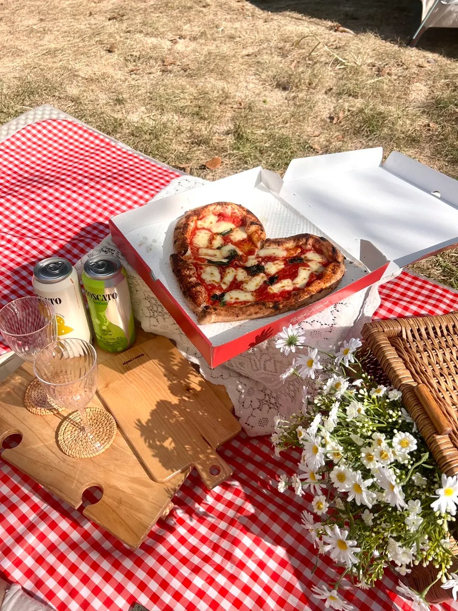 Heart-shaped pizza and canned wine on the box table