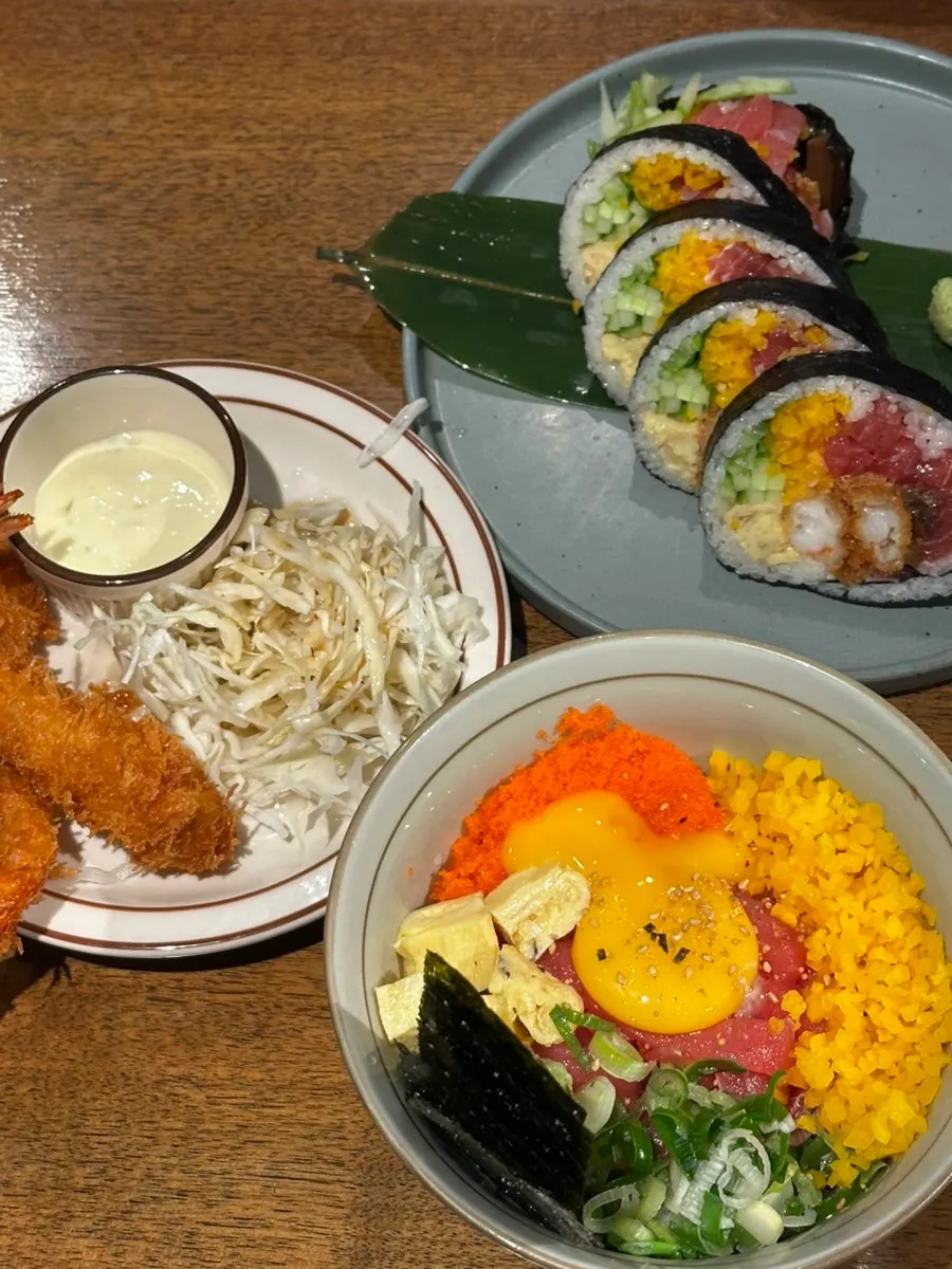 Futomaki, tuna rice bowl, and fried shrimp spread on the table