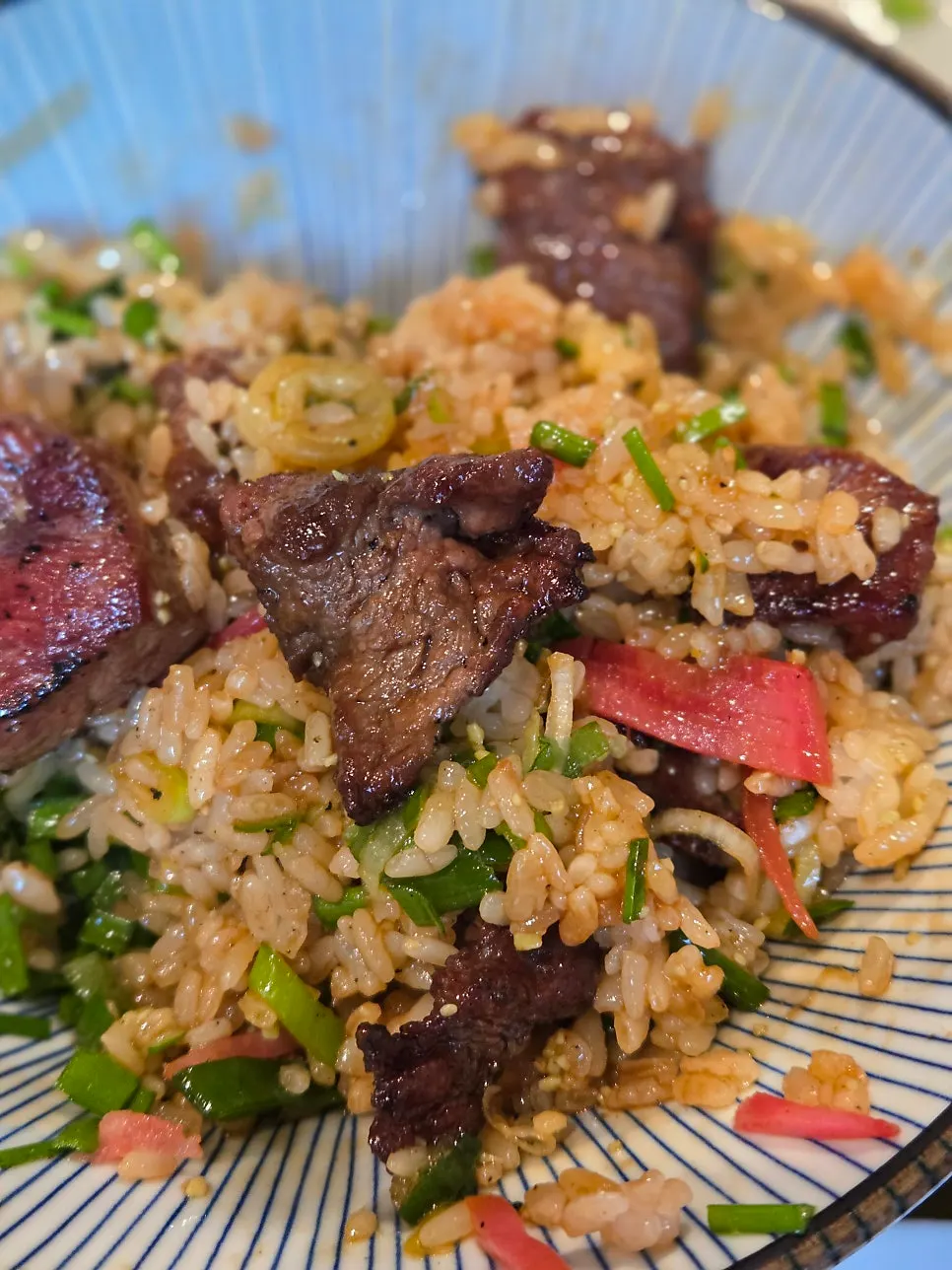 Steak donburi topped with green onion, wasabi, and egg yolk