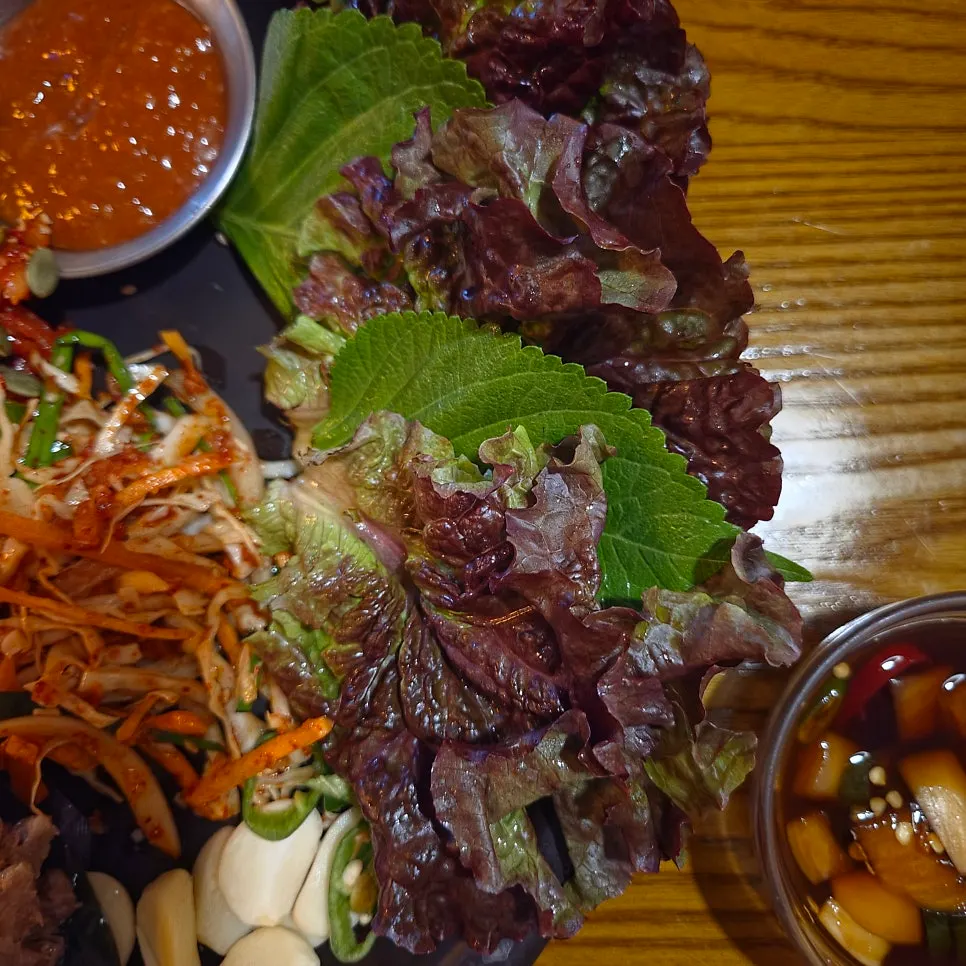 Bossam plated with a perilla leaf and lettuce leaf placed on top