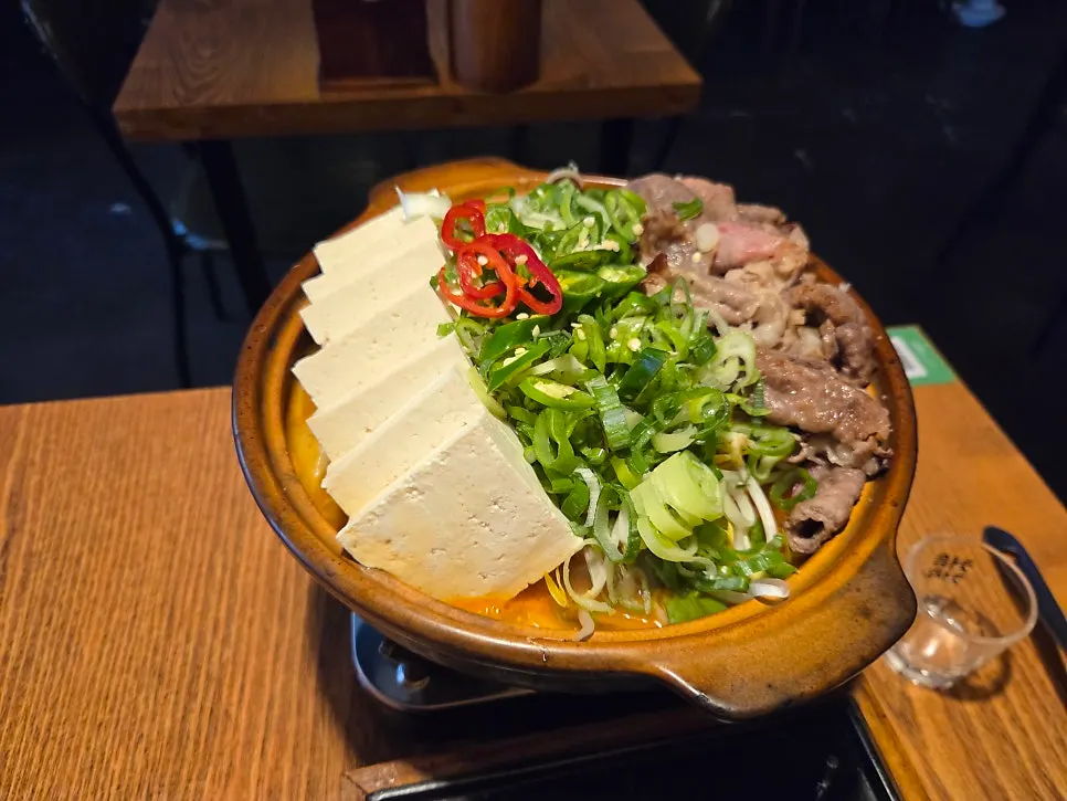 Ladle scooping up doenjang hotpot broth and meat