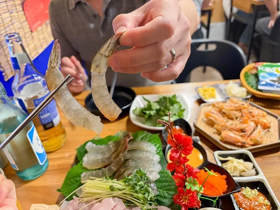 젓가락으로 집어 든 생새우 한 점