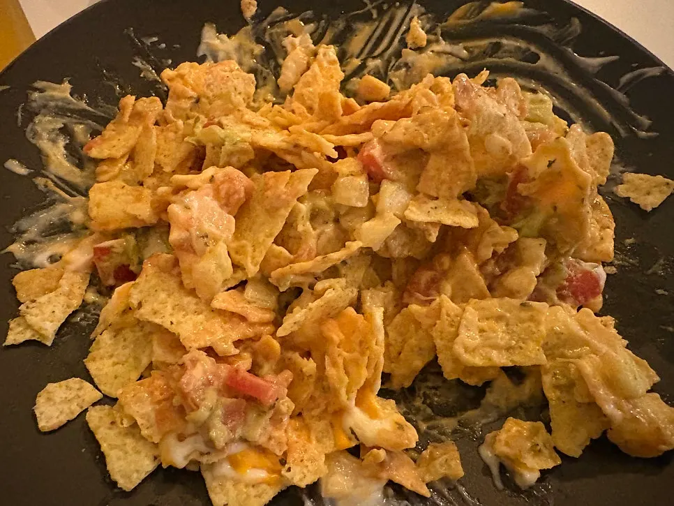 Nachos broken into small pieces with a spoon and mixed with sauce