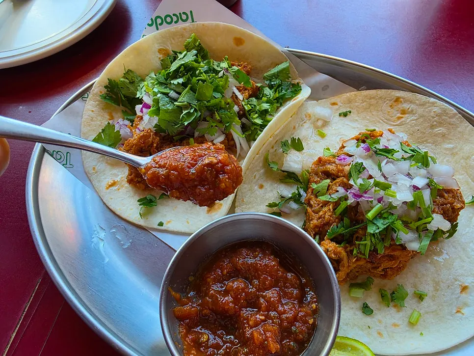 Carnitas taco served with tomato-based sauce