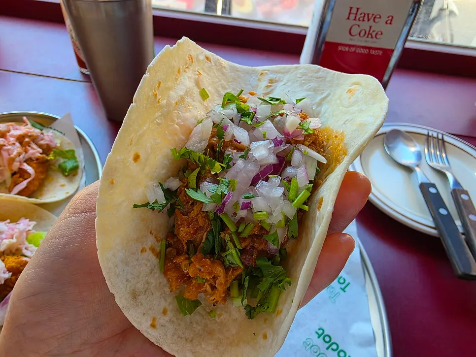 Carnitas taco with lime juice squeezed over it
