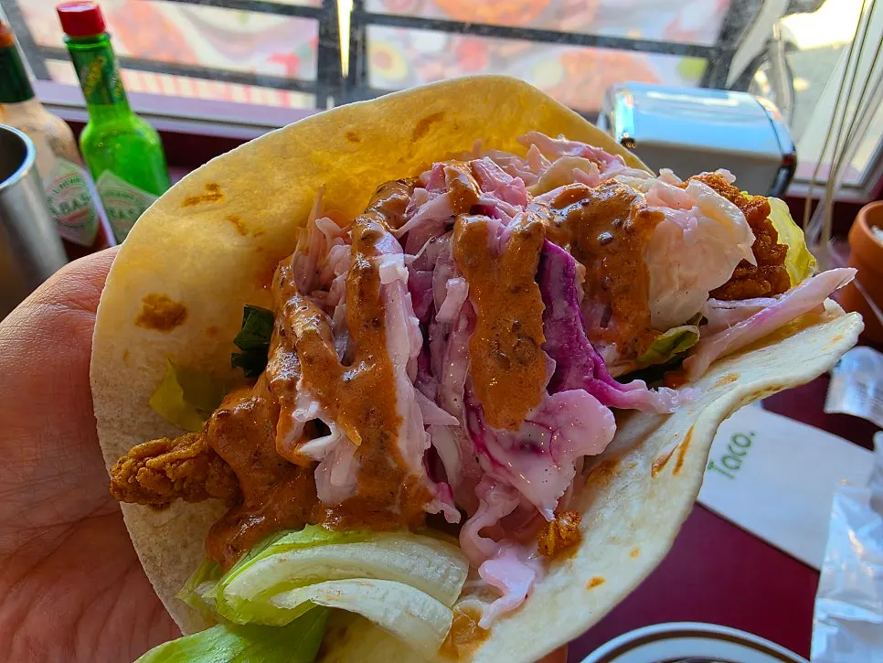 Hot chicken taco topped with coleslaw and chipotle mayo