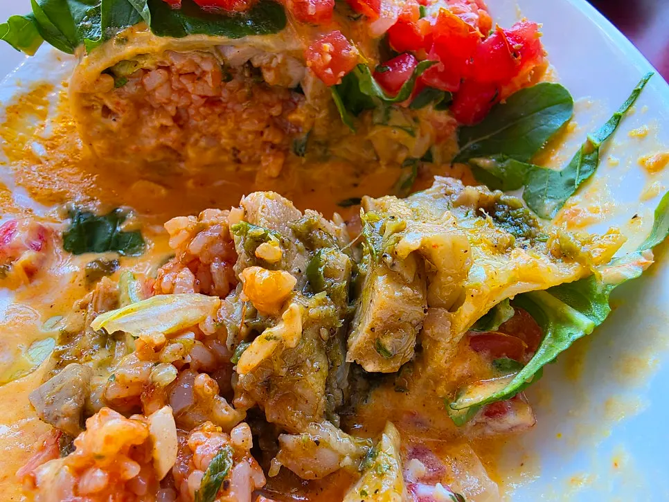 Paprika sauce enchilada topped with chopped tomato and vegetables