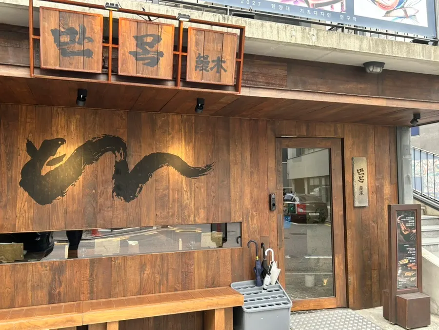 Wood-toned exterior and Manmok's signage