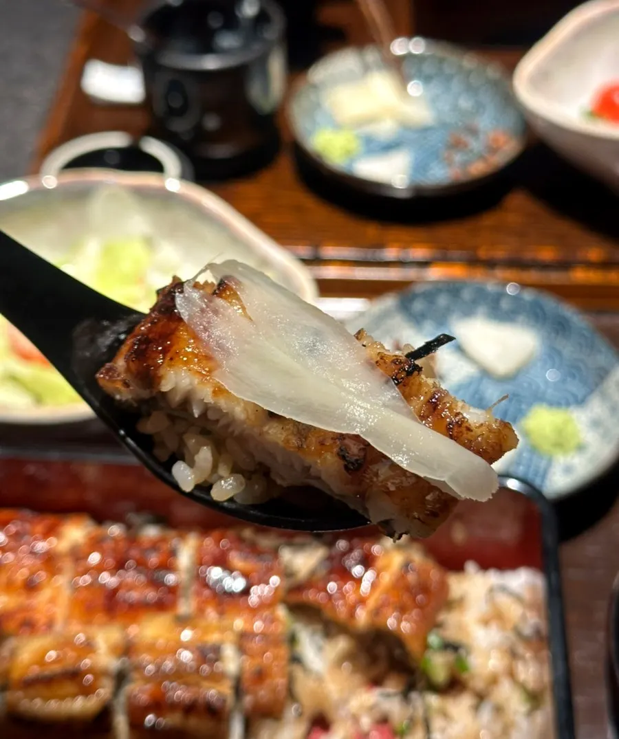 A bite-sized piece of eel picked up with chopsticks