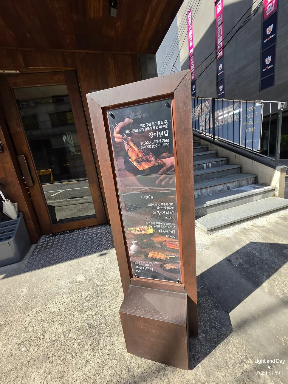 Vertical nameplate and menu standing sign next to Manmok's entrance